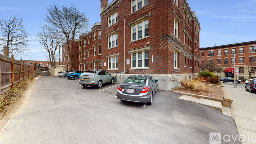 A parking lot with cars and a brick building in the background.
