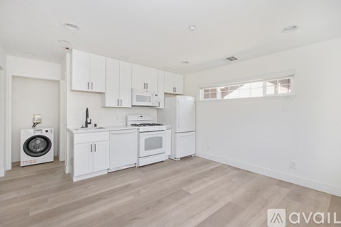 A kitchen with white appliances and cabinets is available for rent.