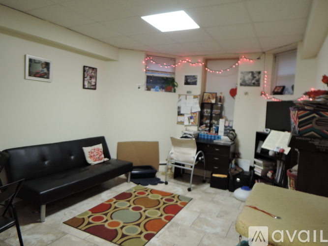 A living room with a black couch and a rug.