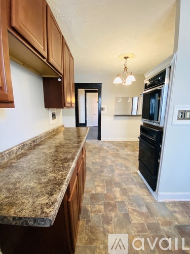 A kitchen with brown cabinets and a marble countertop.