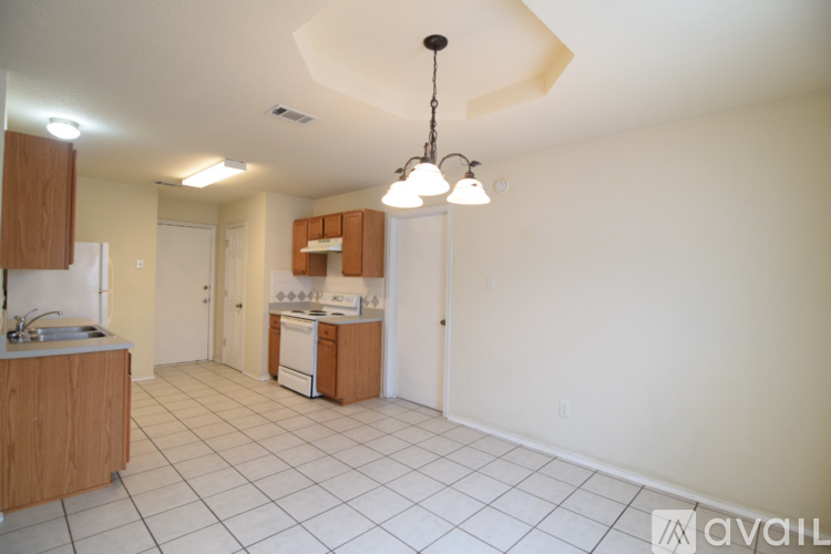 A kitchen with white tiled floors and wooden cabinets.