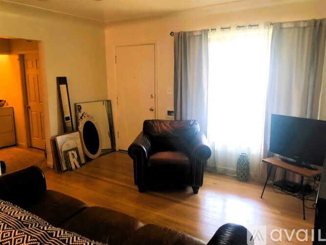 A living room with a black leather couch, a television, and a speaker.