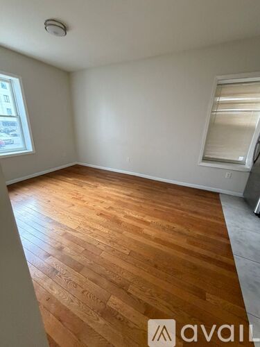 A room with wooden flooring and a window with blinds.