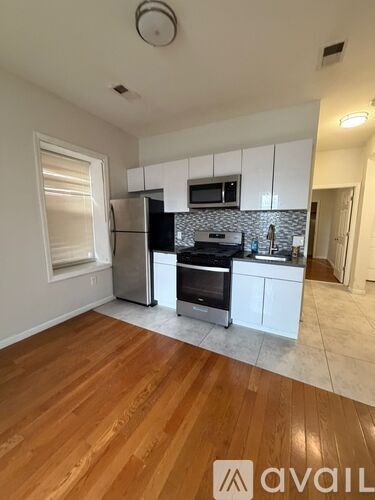 A kitchen with white cabinets and a wooden floor.