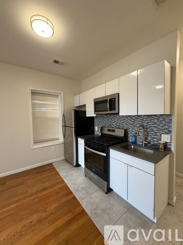 A kitchen with white cabinets and a black fridge.