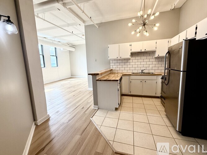 A kitchen with a black refrigerator, white cabinets, and a wooden island.