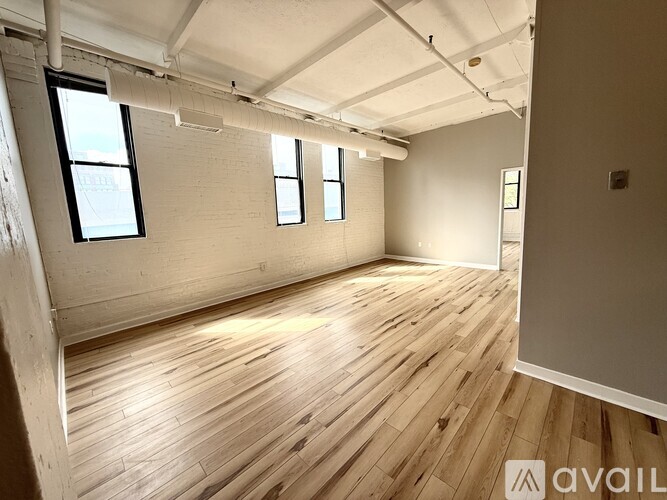 A spacious room with wooden flooring and white walls.