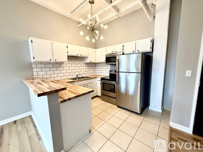 A kitchen with a wooden counter top and stainless steel appliances.