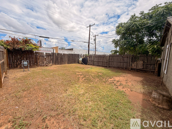A backyard with a wooden fence and a grassy area.