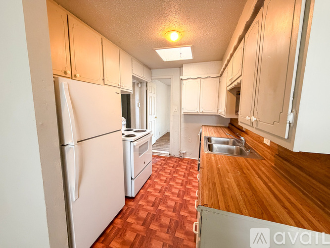 A kitchen with a white refrigerator and wooden floors.