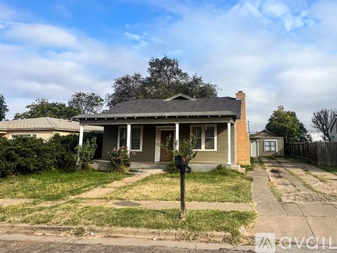 A house with a grey front porch and a mailbox on the sidewalk.