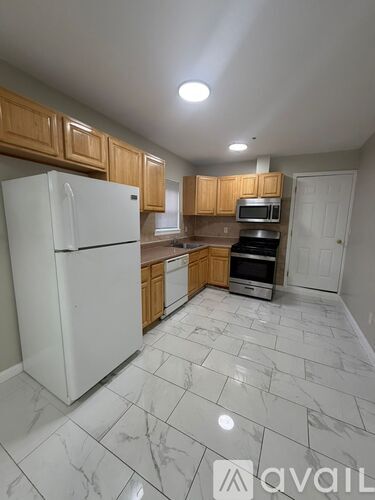 A kitchen with white appliances and wooden cabinets.
