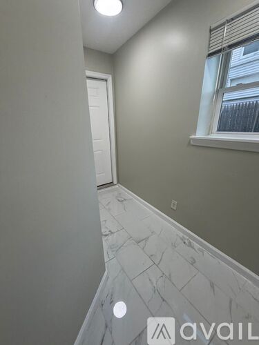 A hallway with marble flooring and a window with blinds.