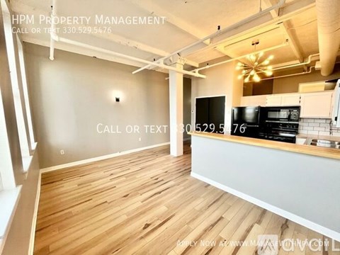 A modern kitchen with a wooden floor and a countertop with a microwave and oven.