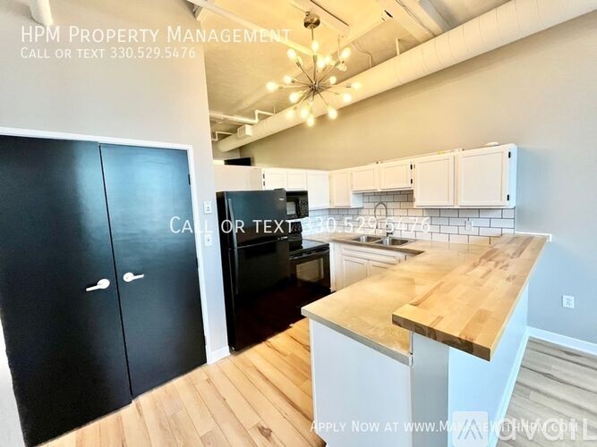 A kitchen with a black door and a wooden countertop is shown.
