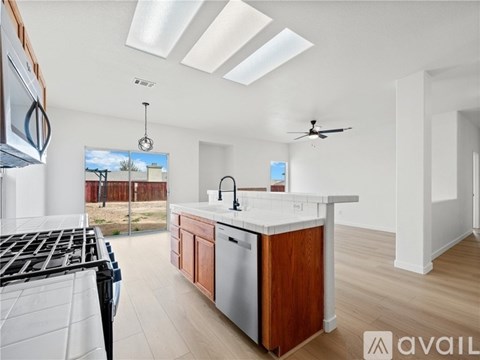 A kitchen with a stove top oven and a dishwasher with a sink and a window.