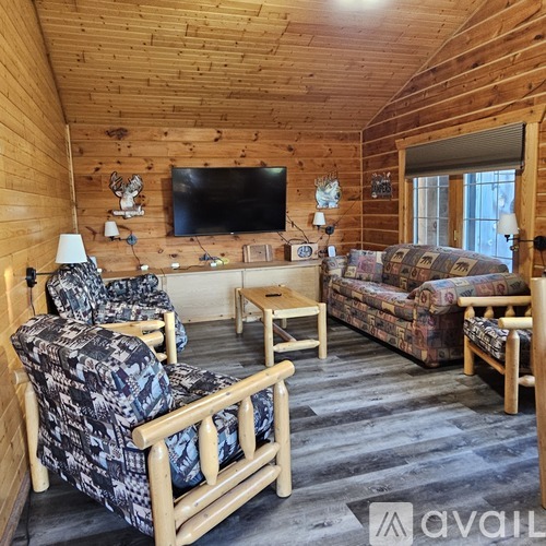 A wooden room with a sofa, chair and a television.