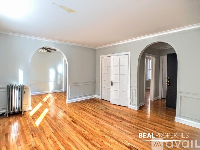 A room with wooden floors and white walls, with a door and a window.