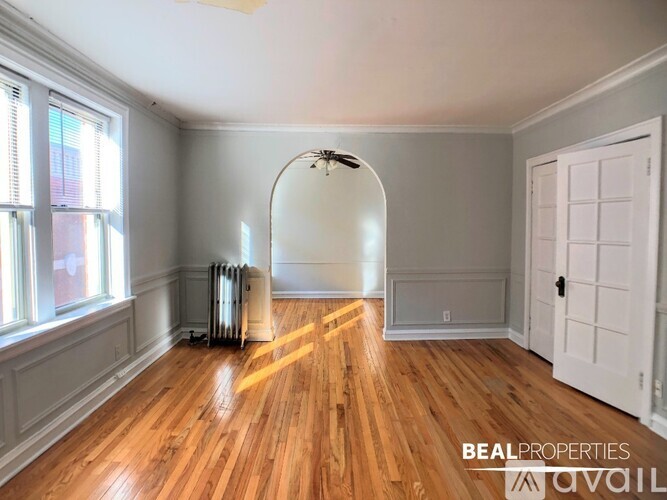 A room with wooden floors and a white door is available for rent.