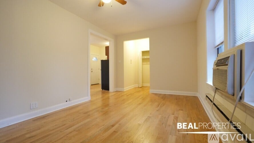A spacious room with wooden floors and a ceiling fan.