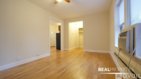 A spacious room with wooden floors and a ceiling fan.