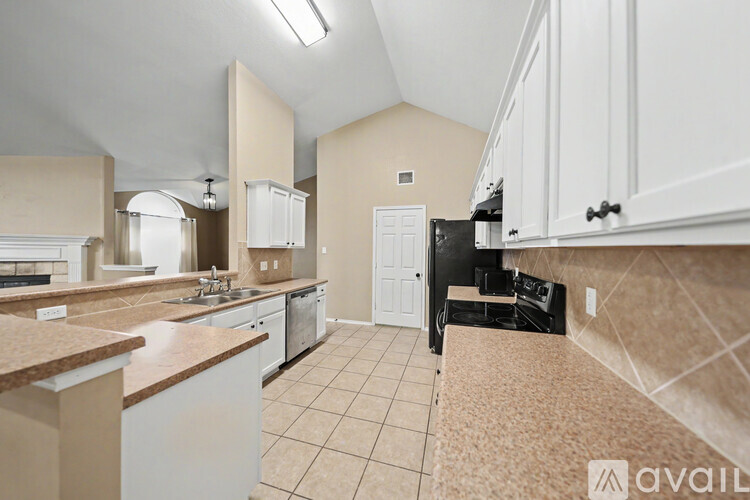 A kitchen with white cabinets and a black refrigerator.