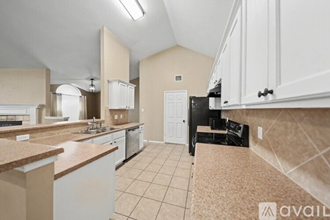 A kitchen with white cabinets and a black refrigerator.