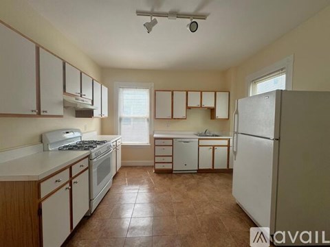 A kitchen with brown tile flooring and white appliances.