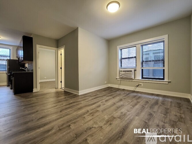 A spacious room with wood flooring and a window with blinds.