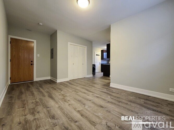 A spacious room with wooden flooring and two doors.