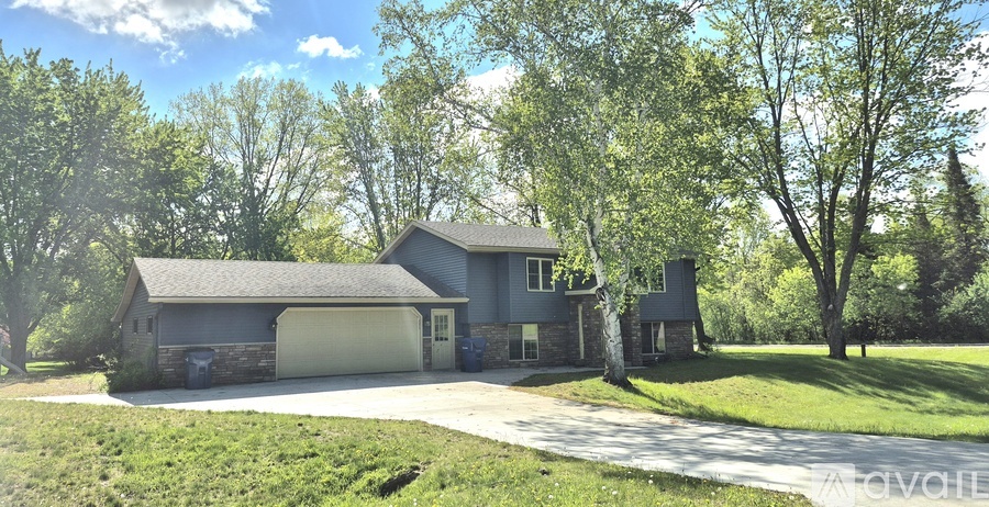 A house with a garage is surrounded by trees.