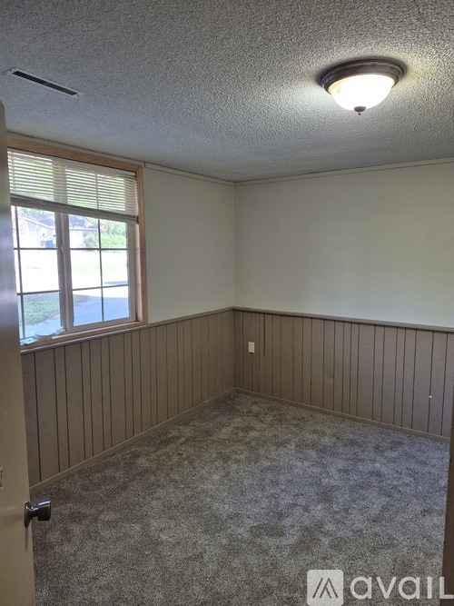 A room with a carpeted floor and a window with blinds.