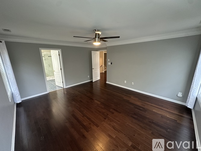 A spacious room with wooden floors and a ceiling fan.