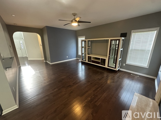 A spacious living room with a ceiling fan and hardwood flooring.