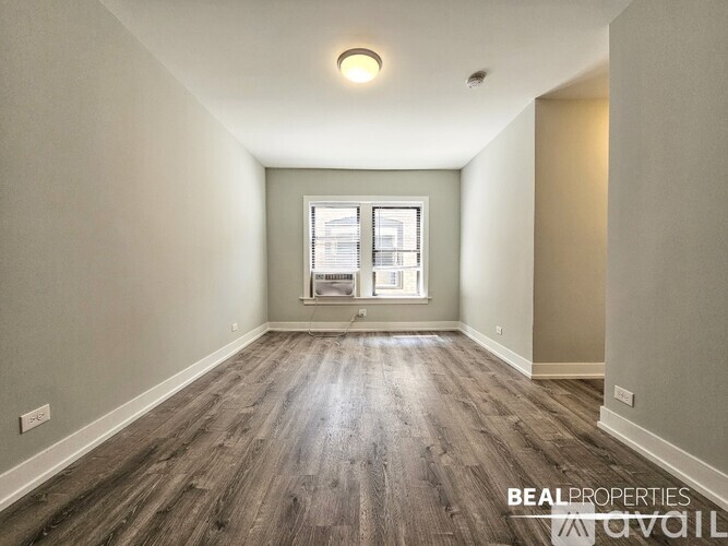 A spacious room with wooden flooring and a window.