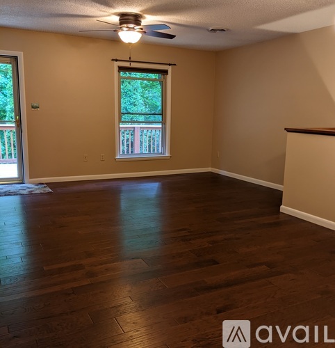 A room with wooden floors and a window with a view of a balcony.