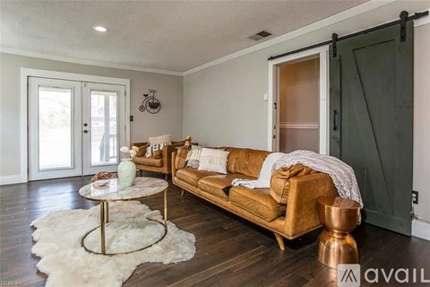A living room with a brown couch and a white rug.