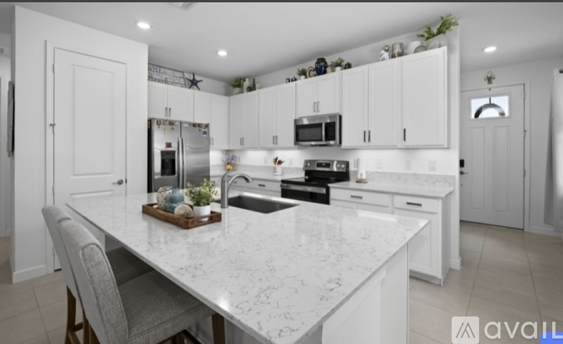 A kitchen with a marble table and white cabinets.