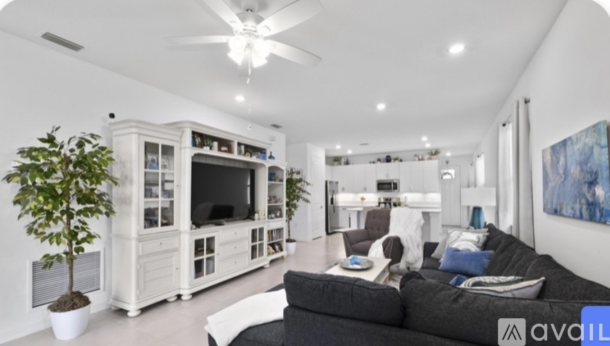 A living room with a black couch and a television on a cabinet.