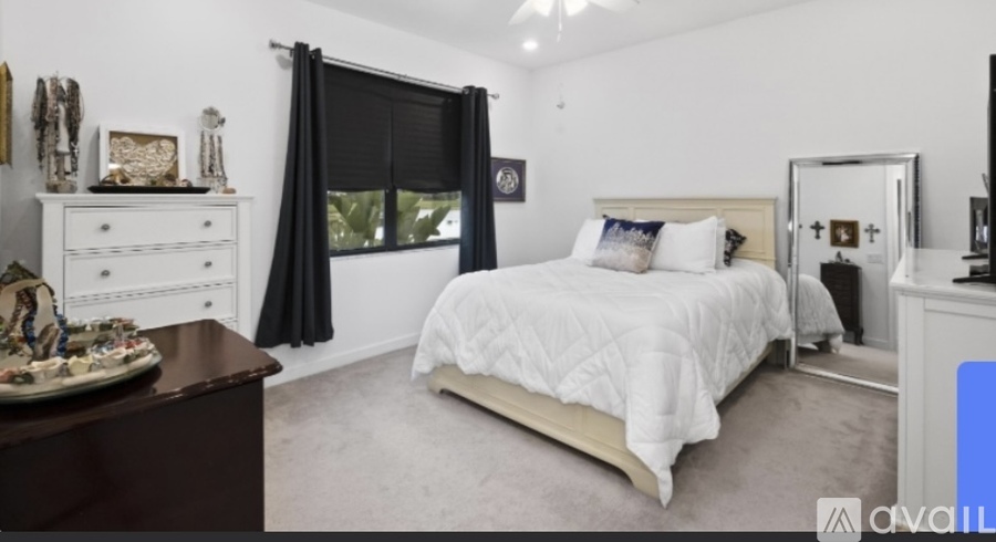 A bedroom with a large bed, a dresser, and a mirror.