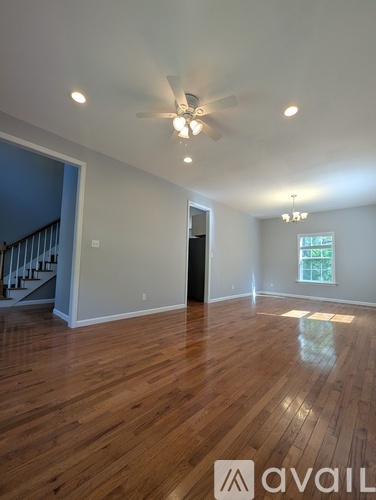 A spacious room with wooden floors and a ceiling fan.
