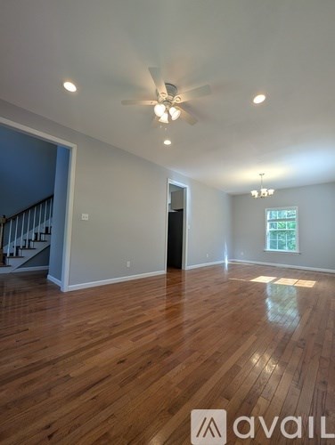 A spacious room with wooden floors and a ceiling fan.