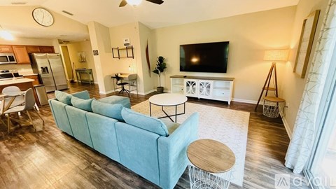 A living room with a blue couch and a television on a white stand.