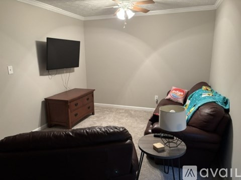 A living room with a brown leather couch, a wooden cabinet, and a ceiling fan.