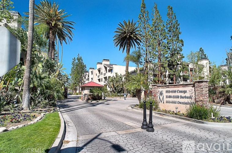A gated community entrance with a sign and palm trees.