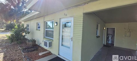 A yellow house with a white door and windows.