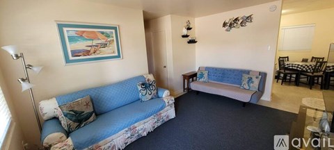 A living room with a blue couch and a painting on the wall.