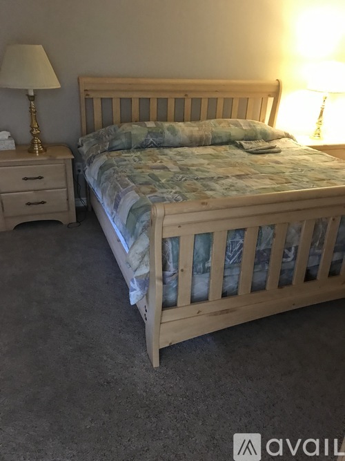 A bedroom with a bed, nightstand, and two lamps.
