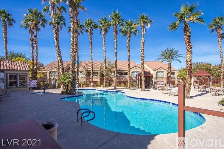 A pool surrounded by palm trees and a building in the background.