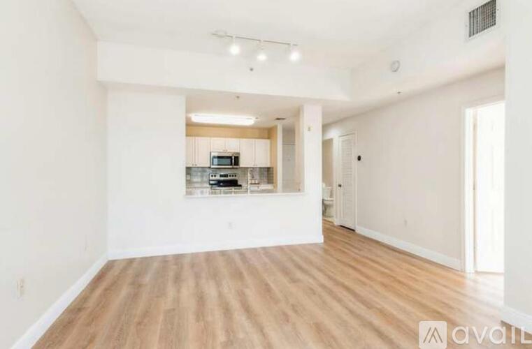 A spacious room with wooden flooring and white walls.